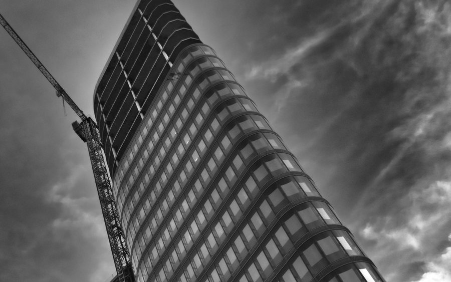 Worker suspended on rope access equipment against a high building facade