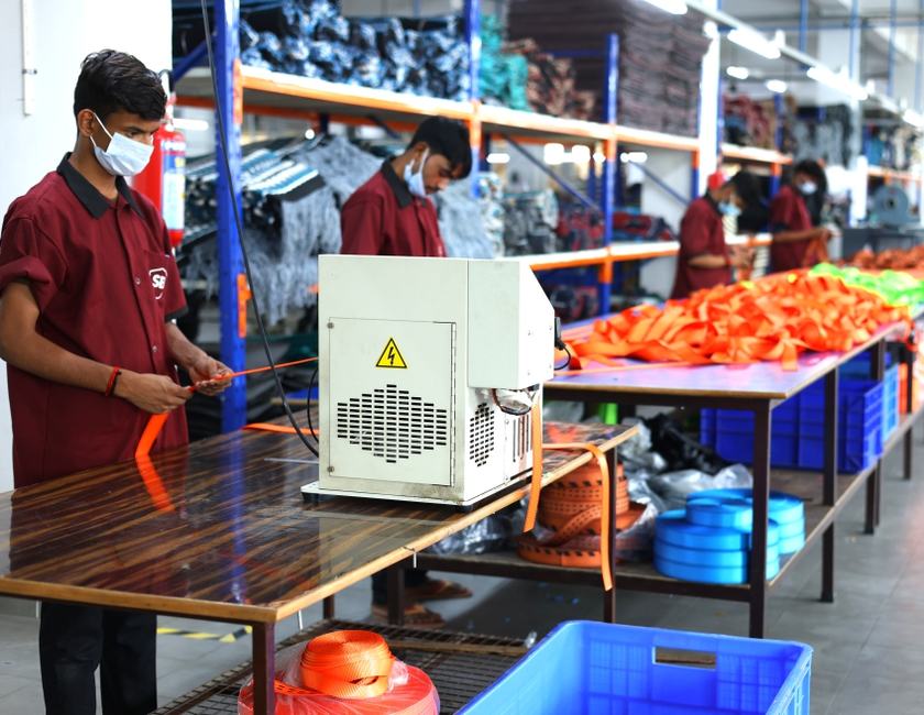 Worker cutting and heat-sealing orange webbing