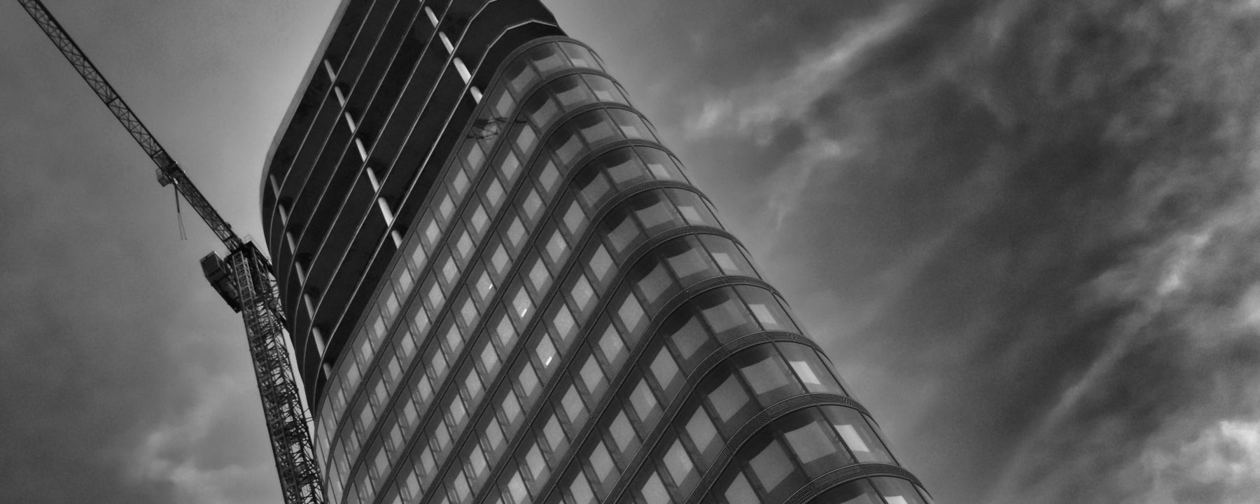 Worker suspended on rope access equipment against a high building facade