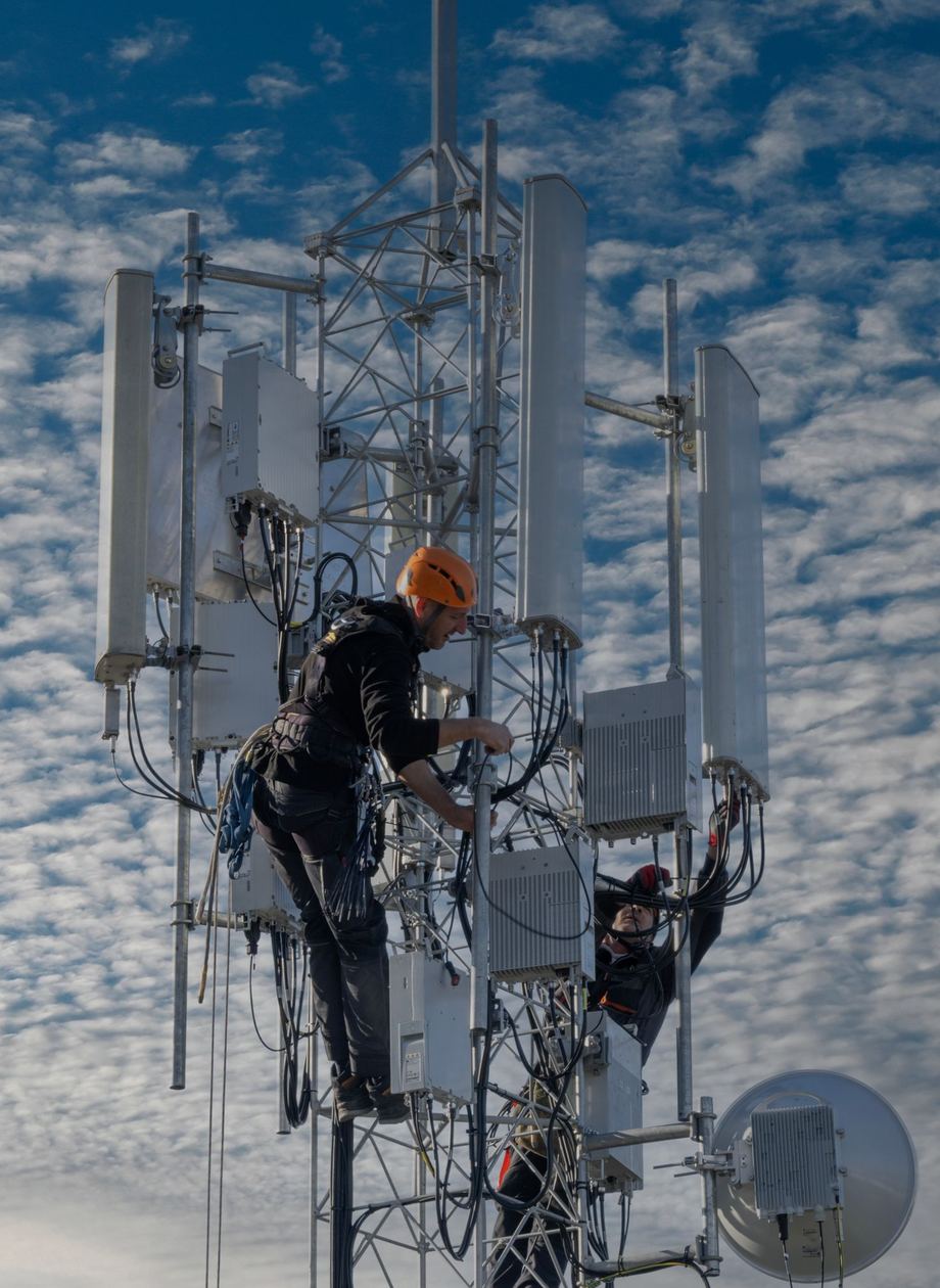 Technicians in harnesses working on a telecom tower